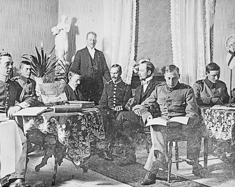 Gammalt svartvitt foto på några män som sitter i ett rum och läser.